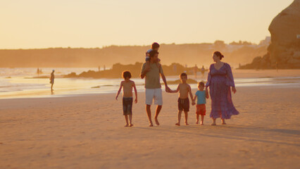 Wonderful family - father, mother and 4 sons (1-8 years old) - walk along one of the most beautiful beaches of Cádiz at sunset - they love and hug each other, look after their children