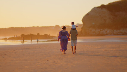 Wonderful family - father, mother and 4 sons (1-8 years old) - walk along one of the most beautiful beaches of Cádiz at sunset - they love and hug each other, look after their children