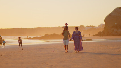 Wonderful family - father, mother and 4 sons (1-8 years old) - walk along one of the most beautiful beaches of Cádiz at sunset - they love and hug each other, look after their children