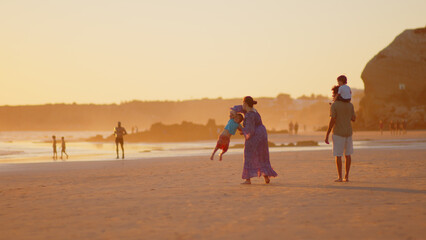 Wonderful family - father, mother and 4 sons (1-8 years old) - walk along one of the most beautiful beaches of Cádiz at sunset - they love and hug each other, look after their children