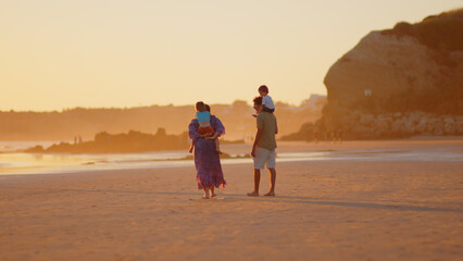 Wonderful family - father, mother and 4 sons (1-8 years old) - walk along one of the most beautiful beaches of Cádiz at sunset - they love and hug each other, look after their children