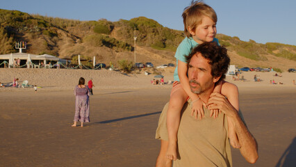 Wonderful family - father, mother and 4 sons (1-8 years old) - walk along one of the most beautiful beaches of Cádiz at sunset - they love and hug each other, look after their children