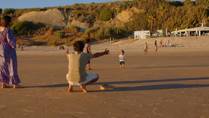 Wonderful family - father, mother and 4 sons (1-8 years old) - walk along one of the most beautiful beaches of Cádiz at sunset - they love and hug each other, look after their children