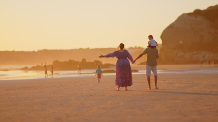 Wonderful family - father, mother and 4 sons (1-8 years old) - walk along one of the most beautiful beaches of Cádiz at sunset - they love and hug each other, look after their children