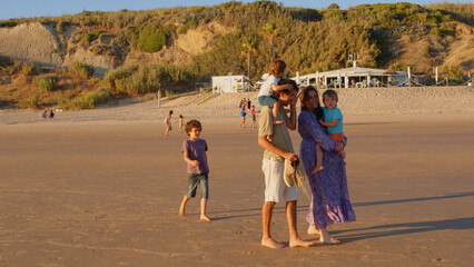 Wonderful family - father, mother and 4 sons (1-8 years old) - walk along one of the most beautiful beaches of Cádiz at sunset - they love and hug each other, look after their children