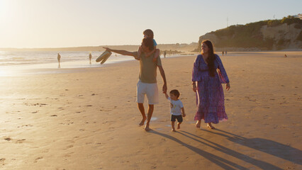 Wonderful family - father, mother and 4 sons (1-8 years old) - walk along one of the most beautiful beaches of Cádiz at sunset - they love and hug each other, look after their children