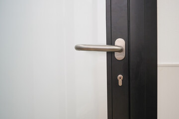 Detail of door lock with doorknob. Modren style door handle on close black aluminum door with glass. Close-up modern metal handle on black aluminum glass door - obrazy, fototapety, plakaty
