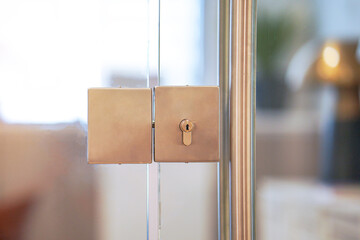 Door lock and doorknob on close glass door in office. Detail of contemporary door lock with...
