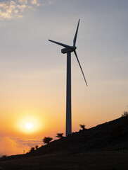 Wind farm on a hill with the sunset in the background.