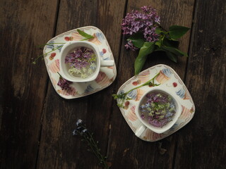 French cup with lilac petals on the table.