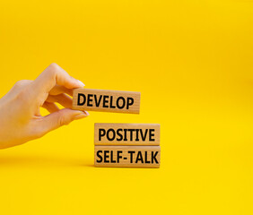 Develop positive self-talk symbol. Concept words Develop positive self-talk on wooden blocks. Beautiful yellow background. Businessman hand. Business and Develop positive self-talk concept. Copy space