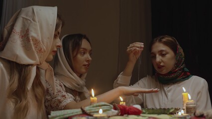 4K. Slavic women are guessing with a ring in a dark room by candlelight
