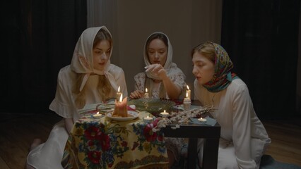 4K. Slavic women are guessing with a ring in a dark room by candlelight