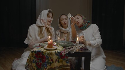 4K. Slavic women are guessing with a ring in a dark room by candlelight