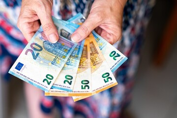 Close-up shot of hands holding 20 and 50 Euro banknotes