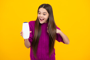 Teenager child girl showing bottle shampoo conditioners or shower gel isolated on yellow background. Hair cosmetic product. Mock up bottle.