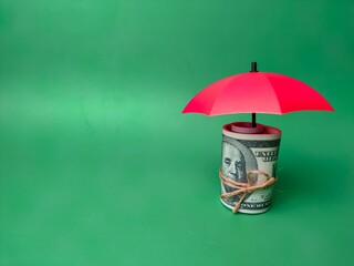 Red umbrella and tied banknotes on a green background prevent risk and the concept of insurance
