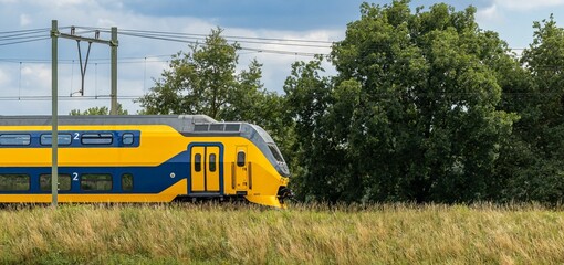 Beautiful shot of NS intercity train on railway road in green field in the Netherlands © Trikiphotography/Wirestock Creators