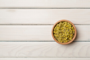 Dried immortelle herbs in bowl on wooden background, top view