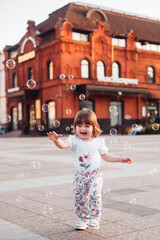 little girl playing on the street with blowing soap bubbles
