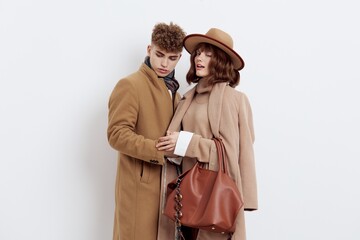 a beautiful, stylish couple, a man and a woman, are standing in autumn coats on a white background, gently snuggling up to each other