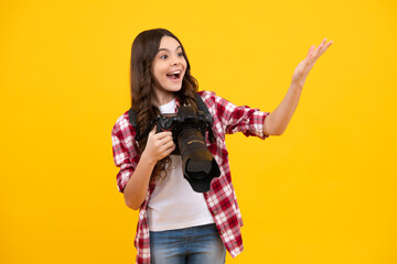 Amazed teenager girl with dslr professional photo camera with big photo lens. Child photographer...
