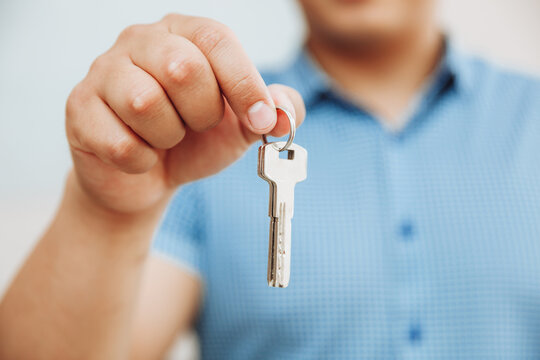 A Business Woman Is Sitting In An Office And Holding Keys In Her Hand.