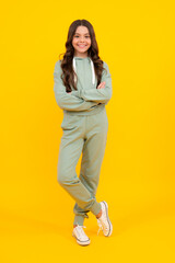 Sporty teenager child wearing a casual sport look. Cute teen girl in sports suit posing over yellow background.