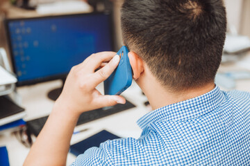 a young Asian businessman is talking on the phone to discuss work in the office. the man is Asian.