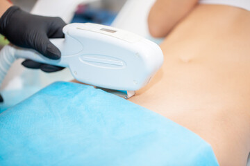 Laser hair removal procedure in a beauty salon. The master cosmetologist removes hair on the patient's face and body using a laser device. Depilation of legs, arms, armpits and bikini area.