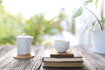 White tea cup and vintage tea pot and small plants on wooden table