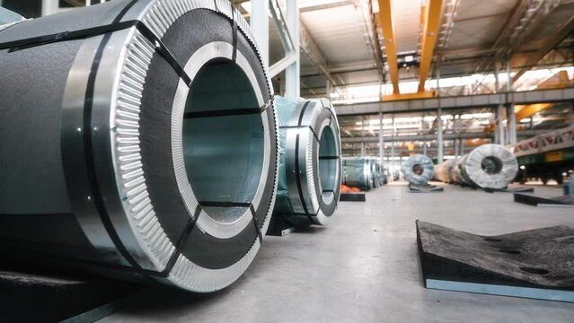 Industrial workshop and warehouse for storage and distribution of products of a metallurgical plant. Coiled steel is stored in rows in a modern warehouse.