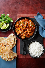 Chicken tikka masala spicy curry meat food Butter chicken, rice and naan bread on red vine dark background. Traditional Indian dish, top view, close up, copy space.