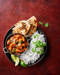 Chicken tikka masala spicy curry meat food Butter chicken, rice and naan bread on red vine dark background. Traditional Indian dish, top view, close up, copy space. - obrazy, fototapety, plakaty