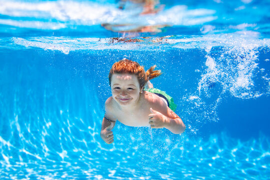 Boy Kid Swim And Dive Underwater. Under Water Portrait In Swim Pool. Child Boy Diving Into A Swimming Pool.