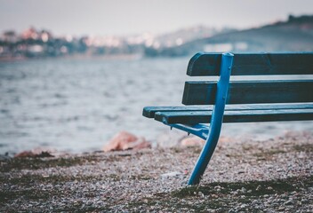 Close-up shot of a blue bench by the seascape