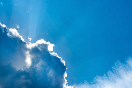 Light ray from sun behind cloud in the blue sky