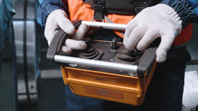 Close-up. Remote control crane beam in an industrial warehouse. The worker is loading and unloading.