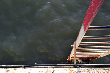Rusty ladder leading to the sea