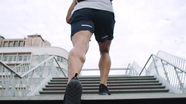 Fit male athlete running for fitness and training for a competitive race in the city alone. Sporty and active man sprinting and doing an outdoor cardio workout before a marathon in town from behind