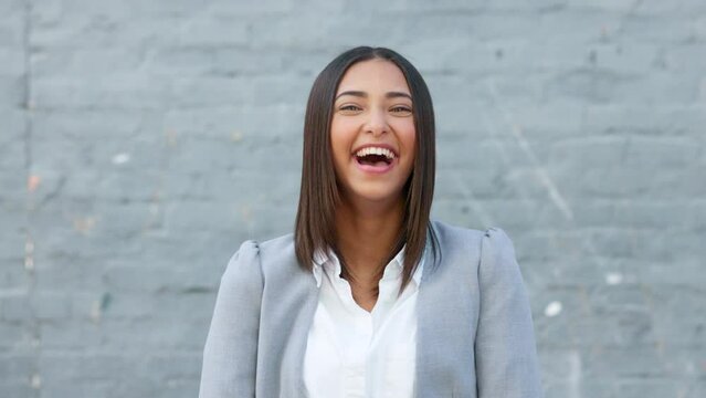 Cheerful woman laughing and giggling about something funny while standing outside against a grey wall with copy space. Happy businesswoman having fun and expressing positivity and a playful attitude