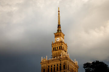 The clock tower of the Palace of Culture and Science in Warsaw, Poland against dramatic clouds.