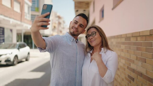 Man and woman mother and daugther make selfie by smartphone at street