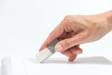 hand holding an eraser over a blank notebook