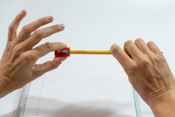 hands sharpening a pencil with a sharpener