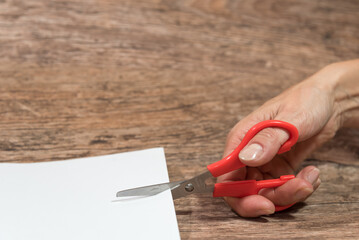 hand cutting a sheet of paper with scissors