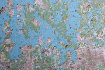 Peeling paint on the wall. Old concrete wall with cracked flaking paint. Weathered rough painted surface with patterns of cracks and peeling. Grunge texture for background and design. High resolution.