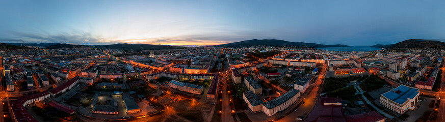 Night panorama of the city of Magadan. A wide panoramic aerial view of a large northern city located in the Russian Far East. Top view of the streets and buildings. Magadan region, Siberia, Russia.