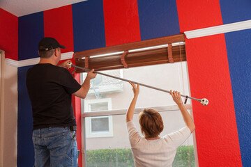 Man and woman installing a curtain in the bedroom