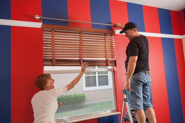 Man and woman installing a curtain in the bedroom